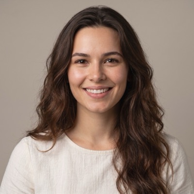 Retrato de Cami Dorta sonriendo, pelo castaño ondulado y remera de lino blanca